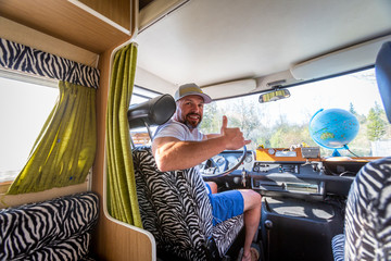 Portrait of careless man during holidays sitting in his van looking at a globe