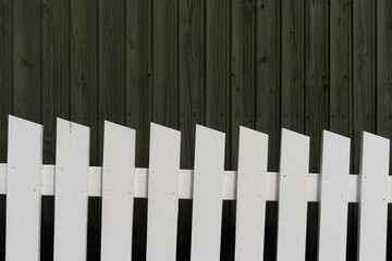 White wooden fence and dark green wood wall cladding. Natural building material background.