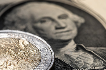 Euro coin on the background of the one dollar banknote