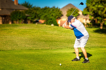 Man teeing off in the tee box, playing golf