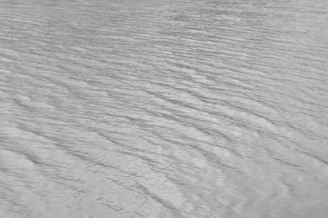 pattern of muddy gray water in a channel with waves and ripples