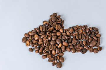 coffee beans scattered in the form of an arrow on a white isolated background