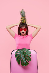 Portrait of a happy asian girl in hat and sunglasses before traveling to warm tropical country on pink background. Open boarders after quarantine
