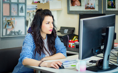 beautiful creative girl sitting at a desk in front of a computer monitor. Designer reflects and...