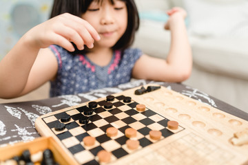 Asian kid girl and mother stay at home lockdown from covid-19 coronavirus crisis are playing chess while spending time together at home.Smart kid home school kid with mom.Stay home Stay safe with mom.