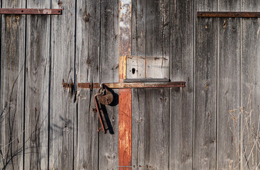 Old wooden barn door with rusty metal padlock.