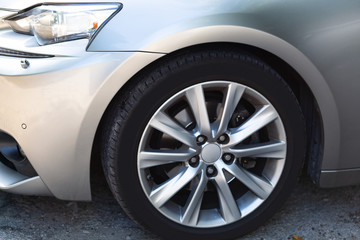 Fototapeta na wymiar Side view on new luxury car wheel on silver metal rim with black shine tire of a modern luxury technology and auto detail