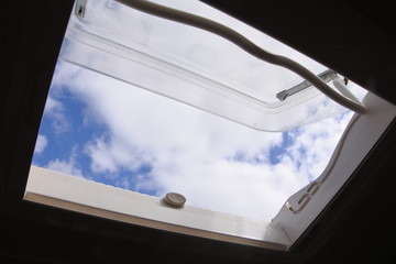 Fototapeta na wymiar Ventana de caravana abierta a un cielo azul con nubes