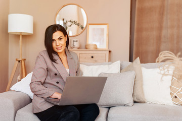 Obraz na płótnie Canvas Businesswoman entrepreneur working on laptop from home sitting on the sofa