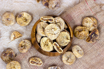 Fototapeta na wymiar Top view of sweet dried italian figs in the wooden bowl on the brown textile background.