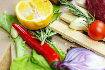 Summer vegetables (onion, garlic, tomato, pepper, rosemary and lemon) on table background.