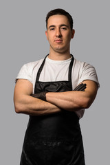 A young man in a white T-shirt with a black apron.