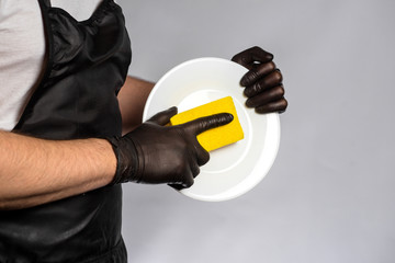 Man in apron and rubber gloves holding a clean plate
