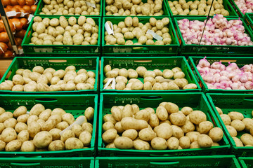 Washed potatoes next to bagged garlic for sale in a commercial market.