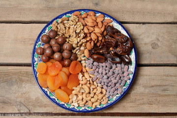 Plate With Assorted Nuts And Dry Fruits With Glass Cup Of Tea. Ramadan Concept. Top View, Flat Lay.