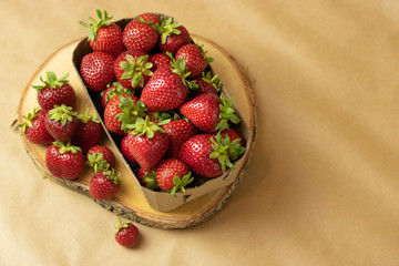 Organic juicy, ripe, red strawberries on a beige background, craft paper. Fresh harvest of farm strawberries