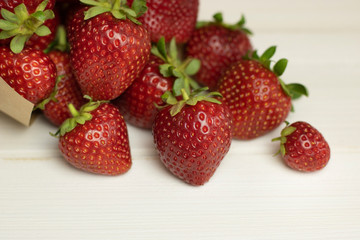 Juicy, ripe, red organic strawberries on a white wooden background. Fresh harvest of farm strawberries on the table