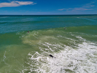 Surfers battle large waves near the shore of Island Beach State Park in New Jersey as they search...
