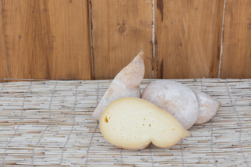 Caciocavallo cheeses, a stretched-curd cheese with teardrop shape Cheese made from cow's milk or sheep's milk. Italian provolone or provola caciocavallo hard and smoked cheeses on wooden background.