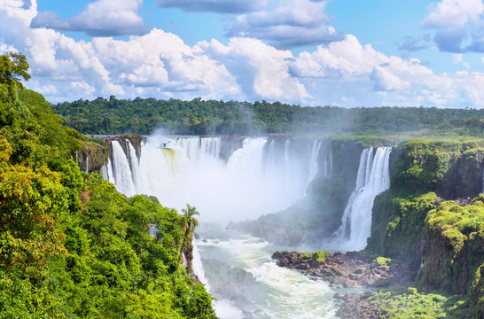 Iguazu waterfalls in Argentina, view from Devil's Mouth. Panoramic view of many majestic powerful water cascades with mist and splashes. Panoramic image of Iguazu riverside, river valley from above.