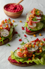 open sandwich with beetroot hummus with vegetables and tomato sauce. Healthy vegan food concept.