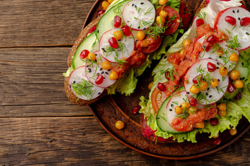 open sandwich with beetroot hummus with vegetables and tomato sauce. Healthy vegan food concept.