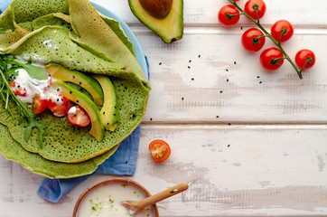Spinach or matcha pancakes with arugula leaves and avocado slices top view