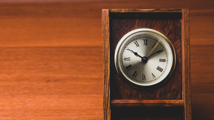 Naklejka premium Retro wooden clock. square shaped vintage clock with round dial. wood table