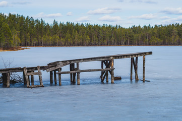 Lonely pier on a frozen lake. wooden jetty on the shore