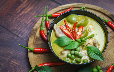 Thai food green curry on soup bowl with ingredient herb vegetable on wooden plate background - green curry chicken cuisine asian food on the table