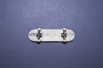 Small skateboard on color background. tiny skate for fingers. fingerboard close up. home leisure...