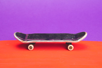 Small skateboard on color background. tiny skate for fingers. fingerboard close up
