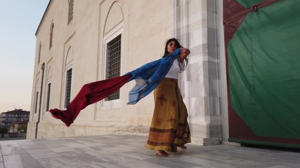 Belly dancer in a brown dress, suit is dancing an oriental, East dance. Beautiful exotic belly tribal dancer with blue and red shawl woman 