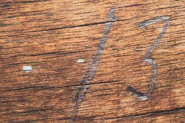 Wood surface with drawn number thirteen. old wooden texture. scratched and cracked background