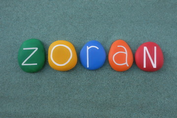 Zoran, common Slavic male given name composed with multi colored stone letters over green sand