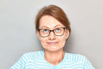 Fototapeta premium Portrait of happy girl with white drops of face cream on skin