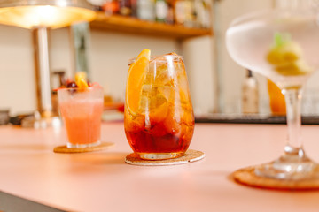 Crystal glass with an iced cocktail with a piece of orange to decorate in a bar