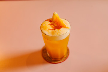 Aerial view of a glass cocktail glass filled with liquid and foam ready to drink and decorated with a piece of orange