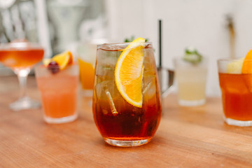 Crystal glass with an iced cocktail with a piece of orange to decorate in a wooden table