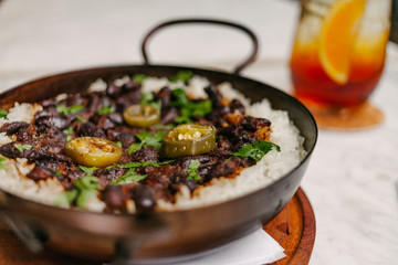 Detail of a pan with rice and beans decorated with chopped green chilies