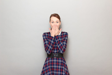 Portrait of shocked frightened girl covering mouth with hands