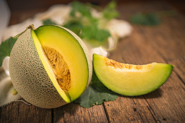 Whole and Slice of Melons with
Leaves on wooden background, yellow melon or cantaloupe melon with seeds isolated on wooden background