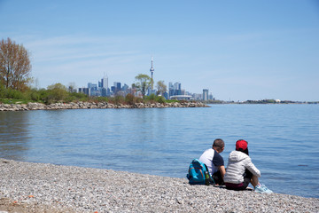 Fototapeta na wymiar couple sitting on the beach with Toronto skyline as the background