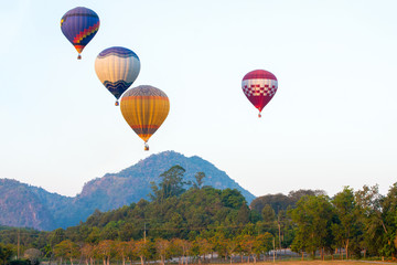 Fototapeta premium beautiful Hot air balloon view on colorful sunset background above trees next to the mountains..