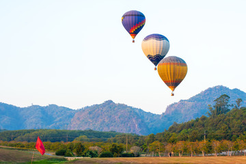 Fototapeta premium beautiful Hot air balloon view on colorful sunset background above trees next to the mountains..