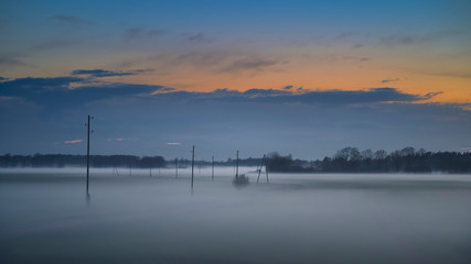 Fototapeta na wymiar Fog layers over agricultural field during spring sunset (high ISO image)