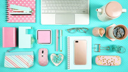Desktop workspace flat lay with hi-tech touch screen laptop and modern pink and aqua blue accessories on blue background