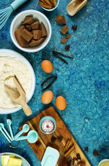 Fototapeta na wymiar Baking flatlay creative composition top view for chocolate recipes including eggs, flour, butter and spices, with cooking accessories on vintage textured blue background table. Vertical orientation.
