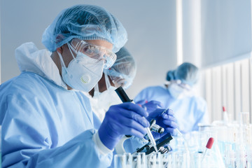 biochemical research scientist team working with microscope for coronavirus vaccine development in...