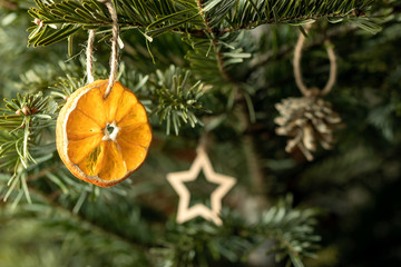 Zero waste christmas concept. Christmas tree decorated with ornaments made of natural materials - slice of dried orange, wooden figures and cones